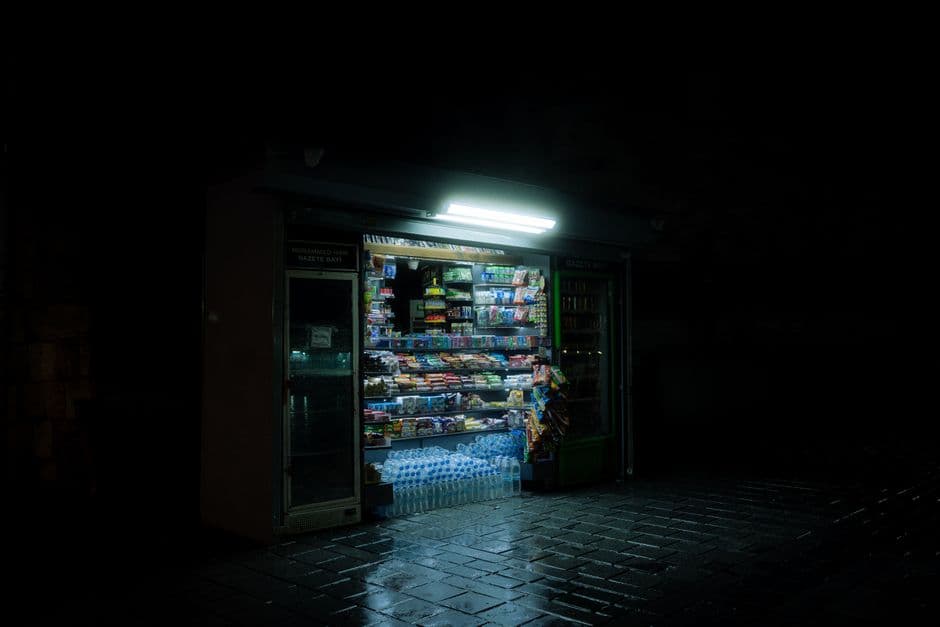Shelves of groceries and a serving counter inside a small independent convenience store