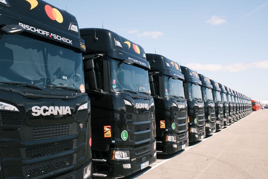 A line of articulated lorries parked at a UK haulage depot at first light, trailers backed to the loading bays