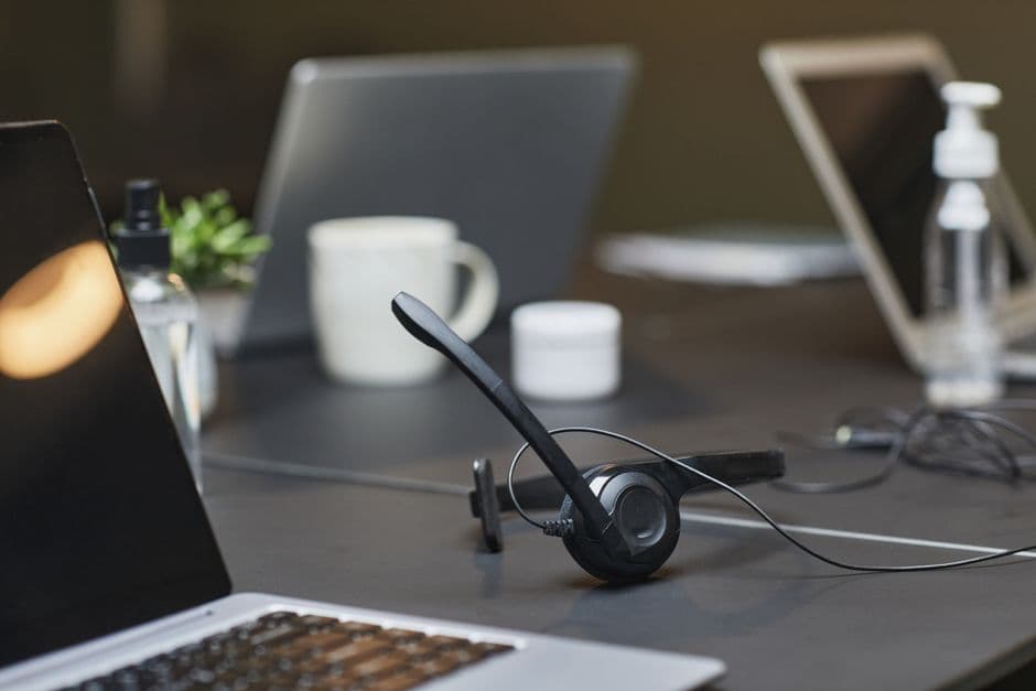 A laptop, notebook and headset on a home desk set up for remote administrative work