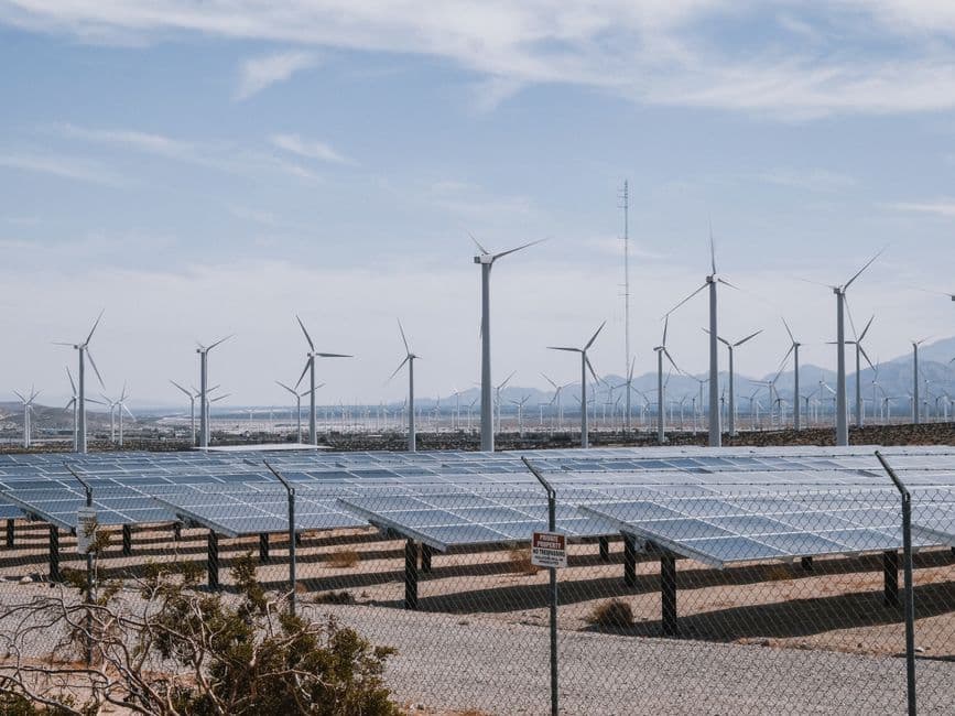 Wind turbines and ground-mounted solar arrays on farmland under a clear sky