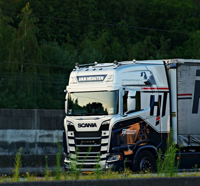 Articulated lorry with a sleeper cab parked overnight in a floodlit motorway truck stop