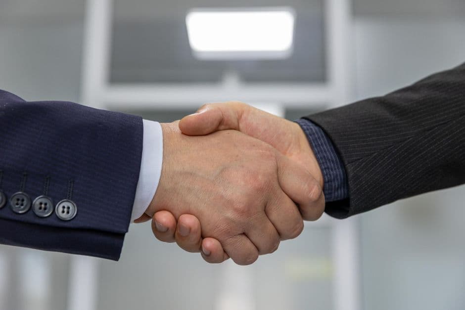 Two business partners reviewing a partnership agreement at a desk in a modern UK office