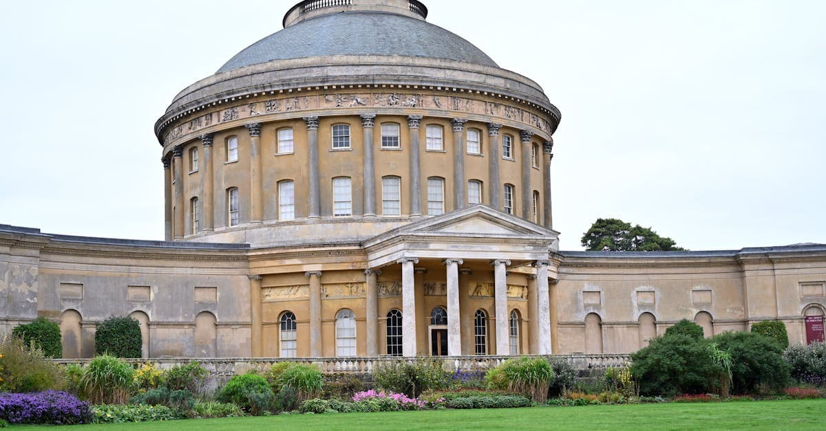 Elegant historic rotunda with columns and lush garden in foreground, showcasing classic architectural style.