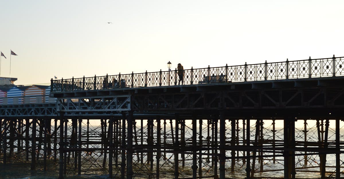 Silhouetted view of Hastings Pier and people walking at sunset.