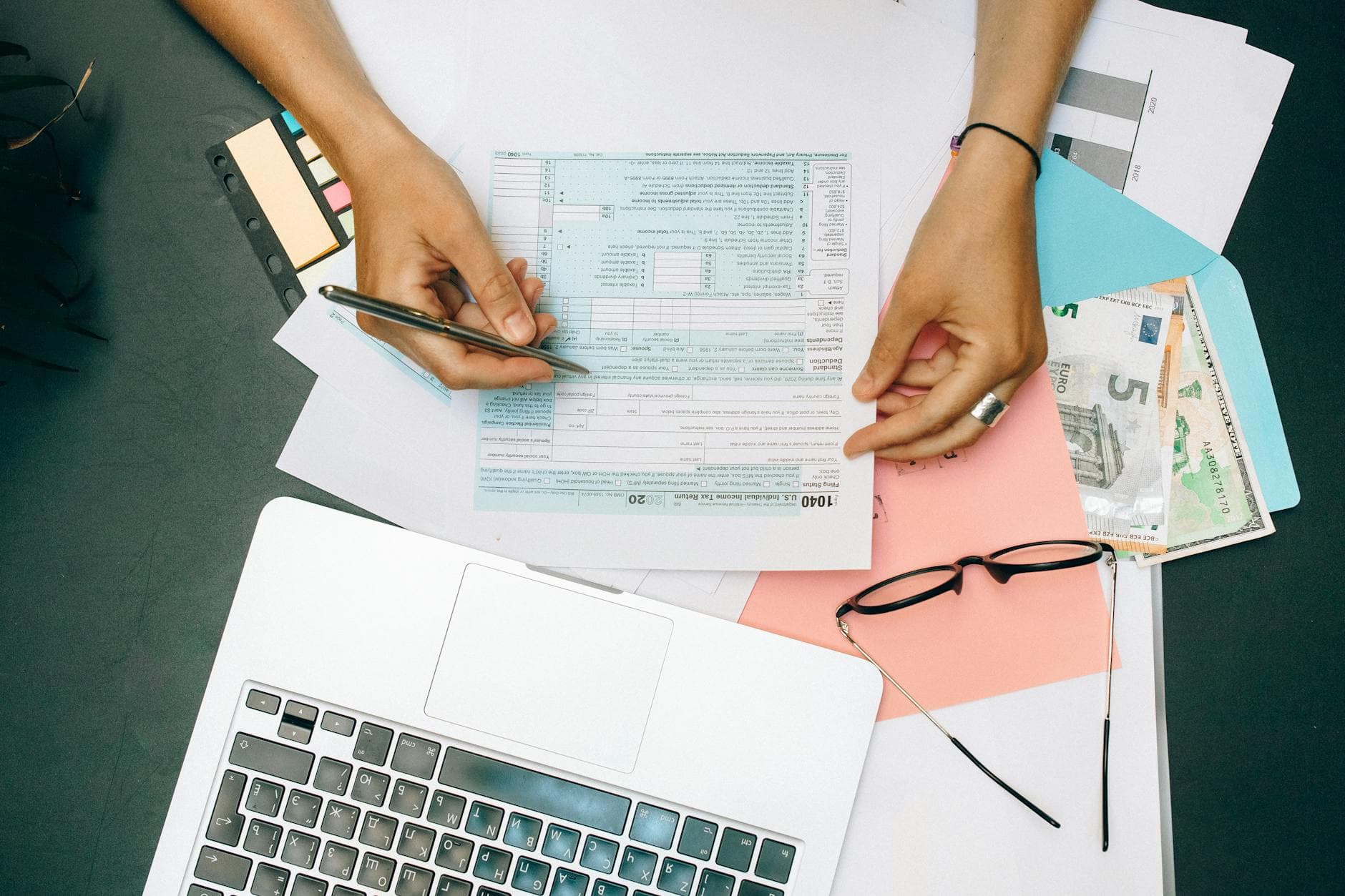 Beauty therapist working at a salon treatment table in a UK city centre, with accounts paperwork visible on a nearby desk