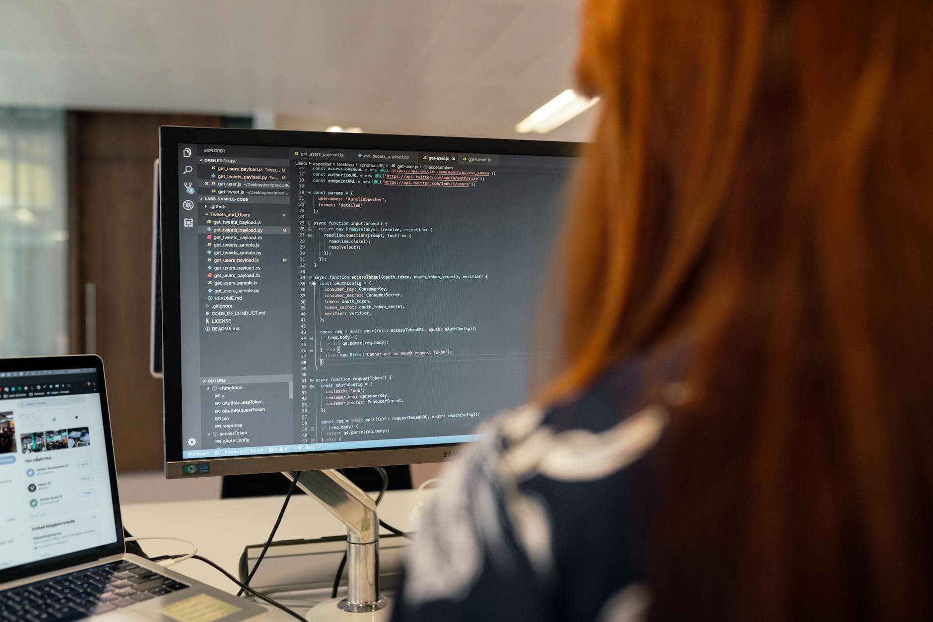 Software engineer working at a desk in a modern UK office with a laptop and accounting paperwork visible