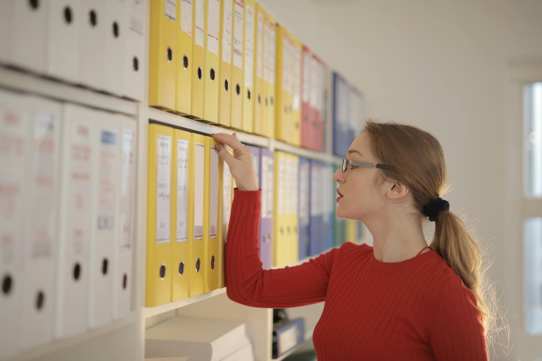 UK accountant reviewing a stack of bookkeeping records for a limited company, with a calculator and paperwork on a desk in a Manchester office.
