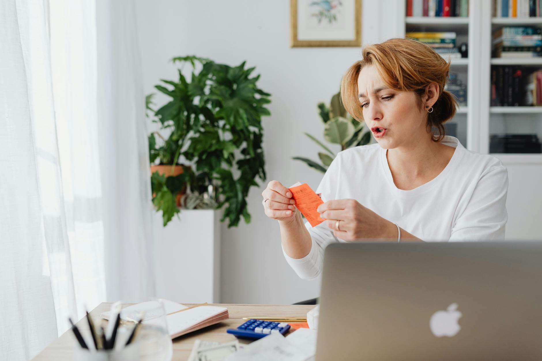 Director working from home at a desk with laptop and paperwork, UK home office setting