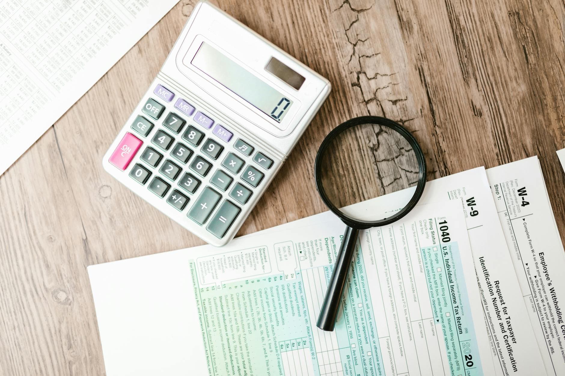 Sole trader working on a laptop with a notebook showing profit calculations for multiple self employed trades in a UK home office
