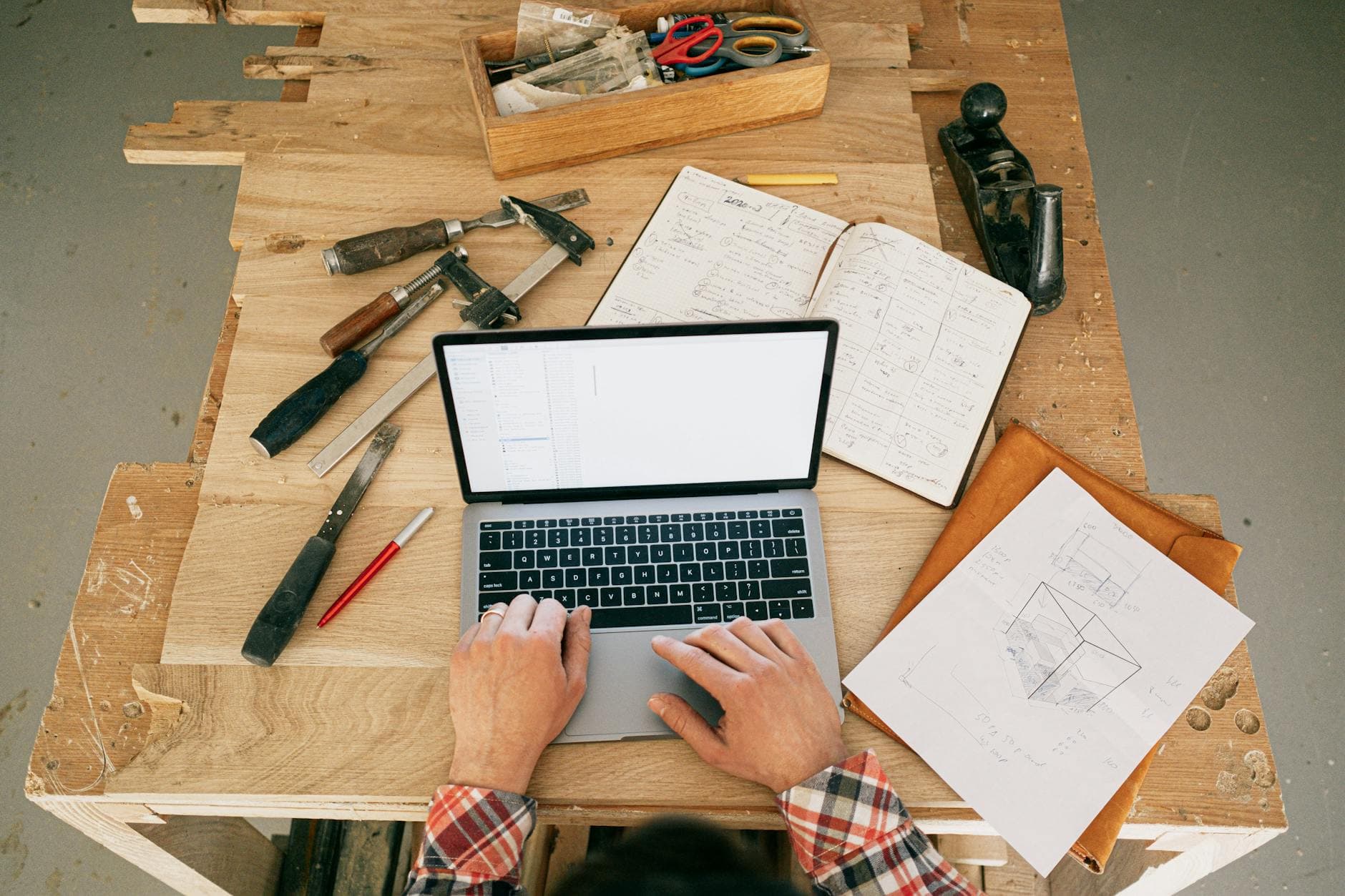 A UK construction site manager and an accountant reviewing financial reports on a laptop at a site office in Manchester.