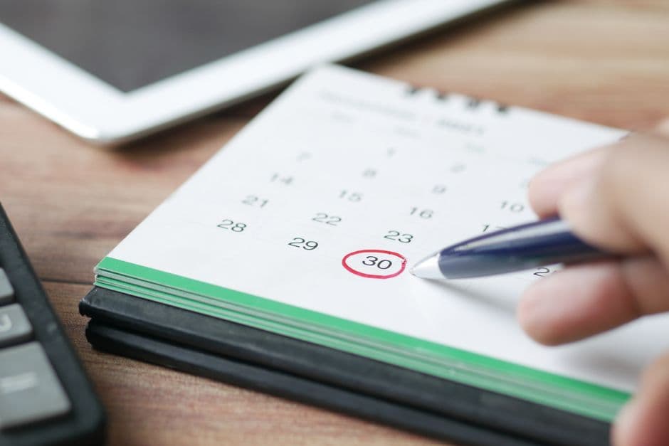 UK accountant reviewing a corporation tax payment schedule on a laptop with a calendar and calculator on the desk