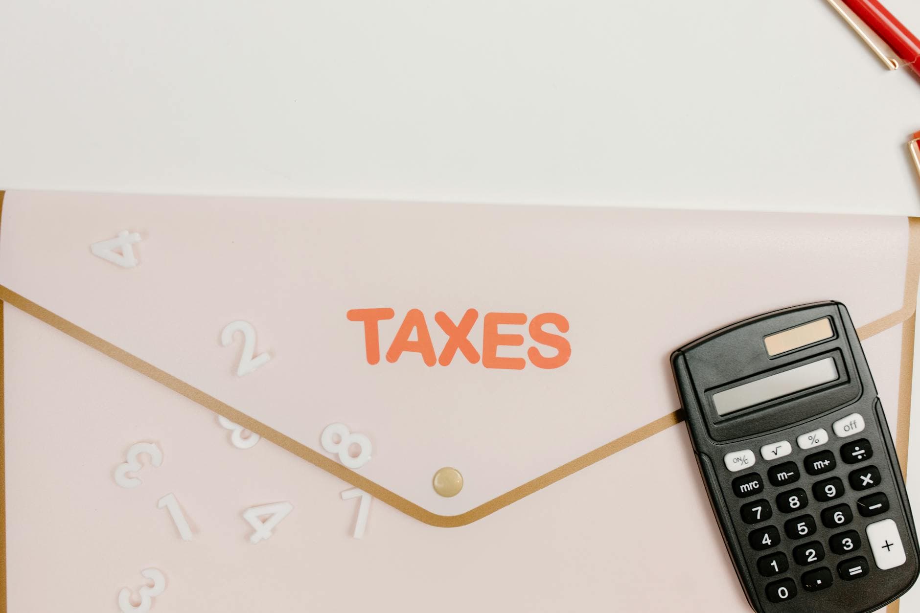 Director reviewing quarterly dividend calculations on a laptop in a modern UK office with a calculator and printed tax tables