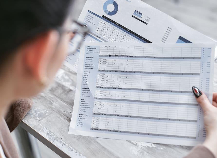 Self employed business owner reviewing a financial spreadsheet of income and expense records at a desk