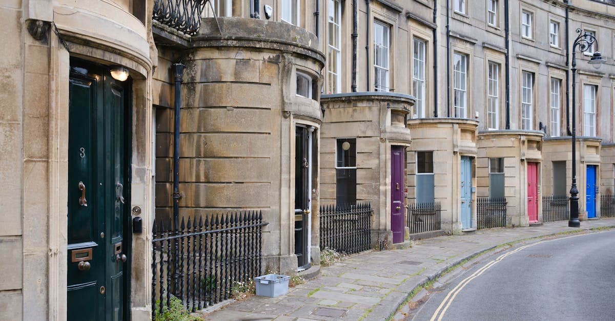 Curved Georgian terrace with colorful doors on a quiet street in Bath, England, showcasing historical architecture.
