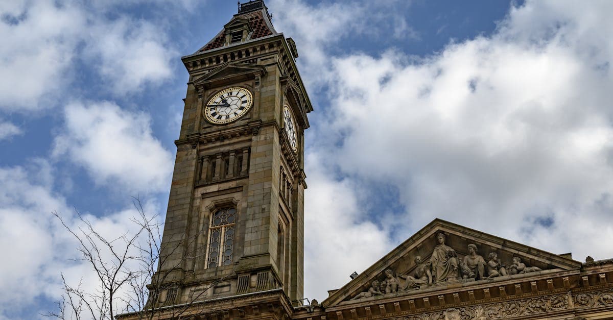 View of the historic Bolton Town Hall clock tower against a cloudy sky in England.