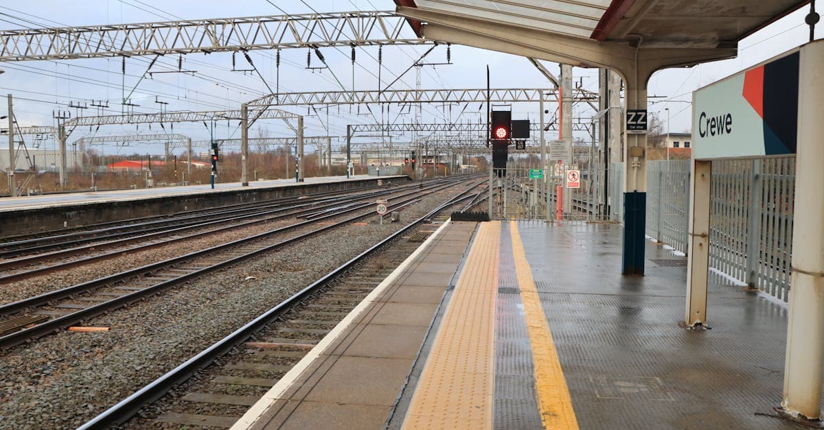 View of an empty platform at Crewe Railway Station, England, showcasing tracks and signage.