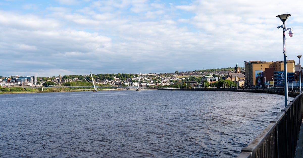 Scenic view of the Peace Bridge spanning the River Foyle in Derry, Ireland under clear blue skies.