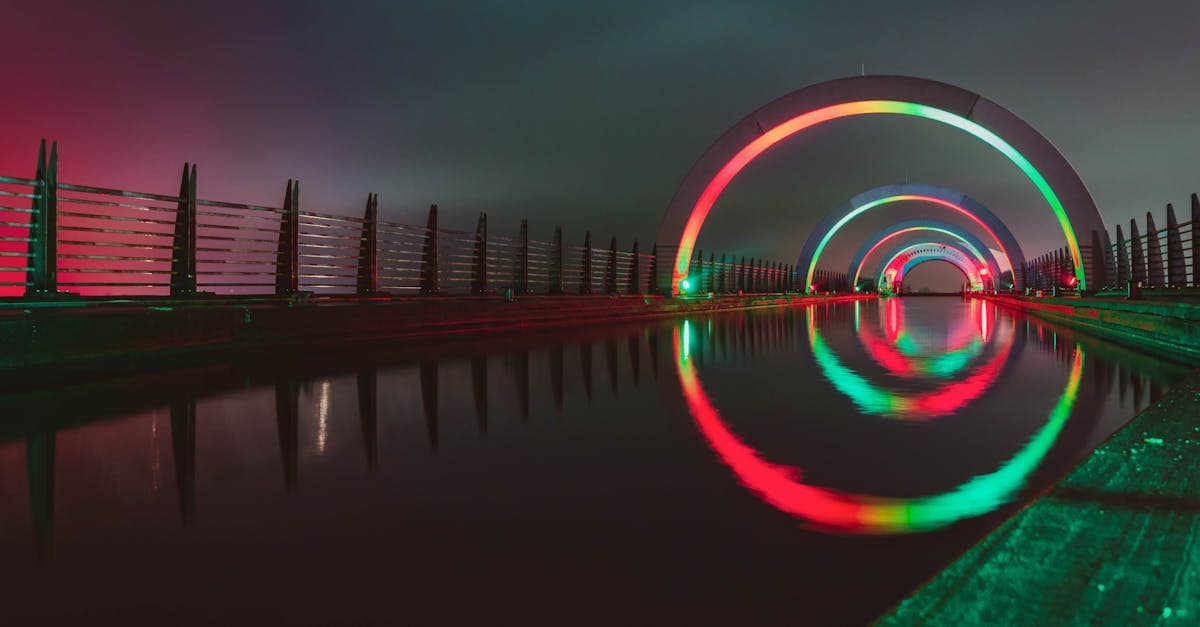 Stunning night view of the illuminated Falkirk Wheel reflecting on calm waters in Scotland.