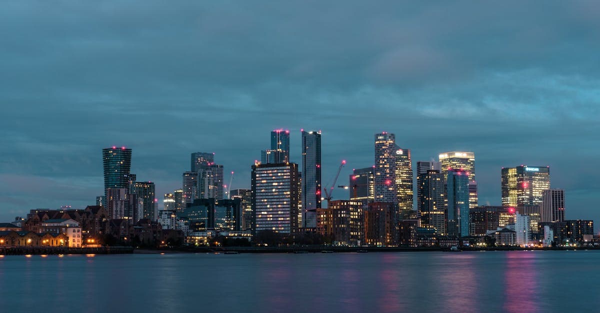 Evening view of the illuminated skyline of Canary Wharf, reflected on water, United Kingdom.