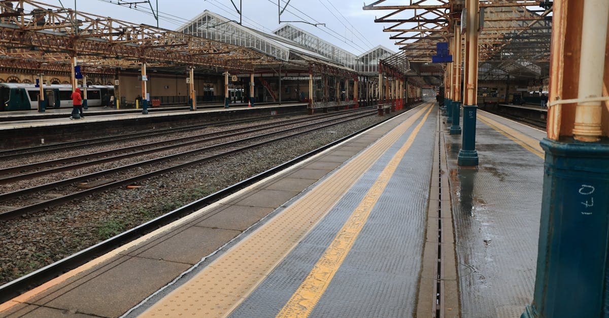 An empty train station platform in the UK, showcasing classic architecture on a rainy day.