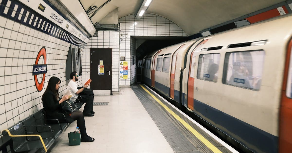 Commuters waiting at Leicester Square station with a train passing by.
