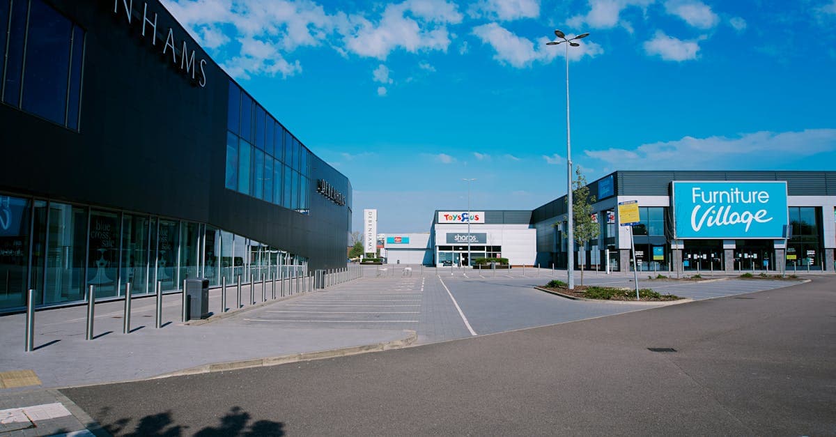 A modern shopping mall exterior in England with large signs and parking area.