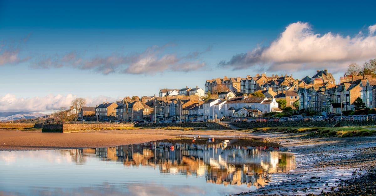 Charming village of Arnside, England, reflected in calm waters under a vibrant sky.