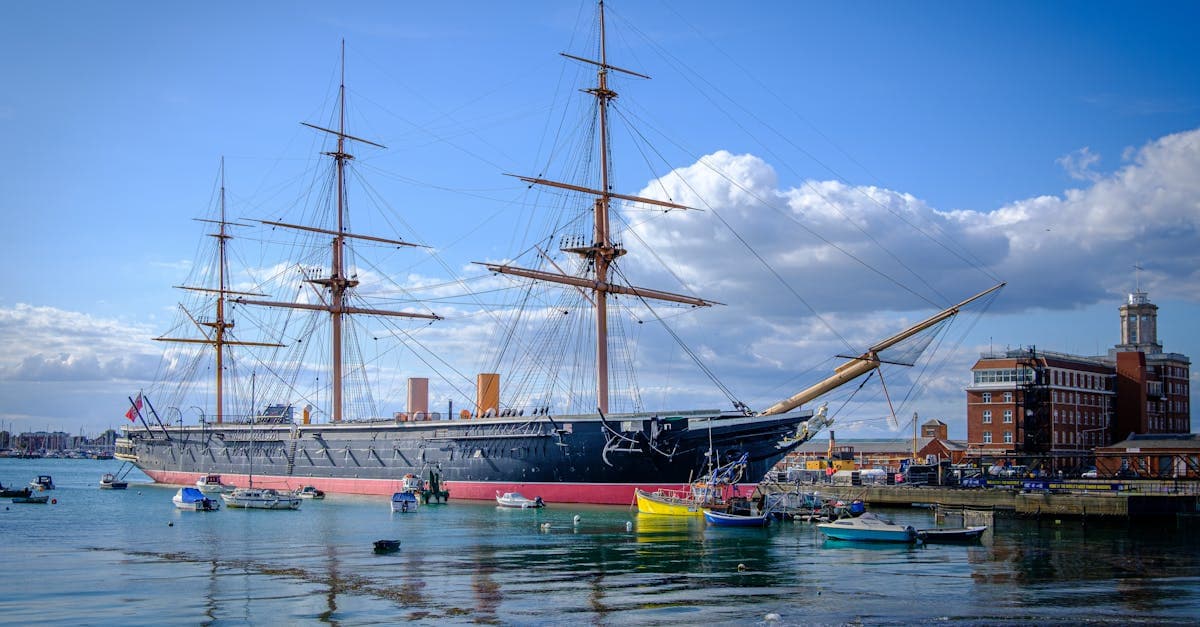 The iconic HMS Warrior, a 19th-century warship, docked in Portsmouth under a clear blue sky.