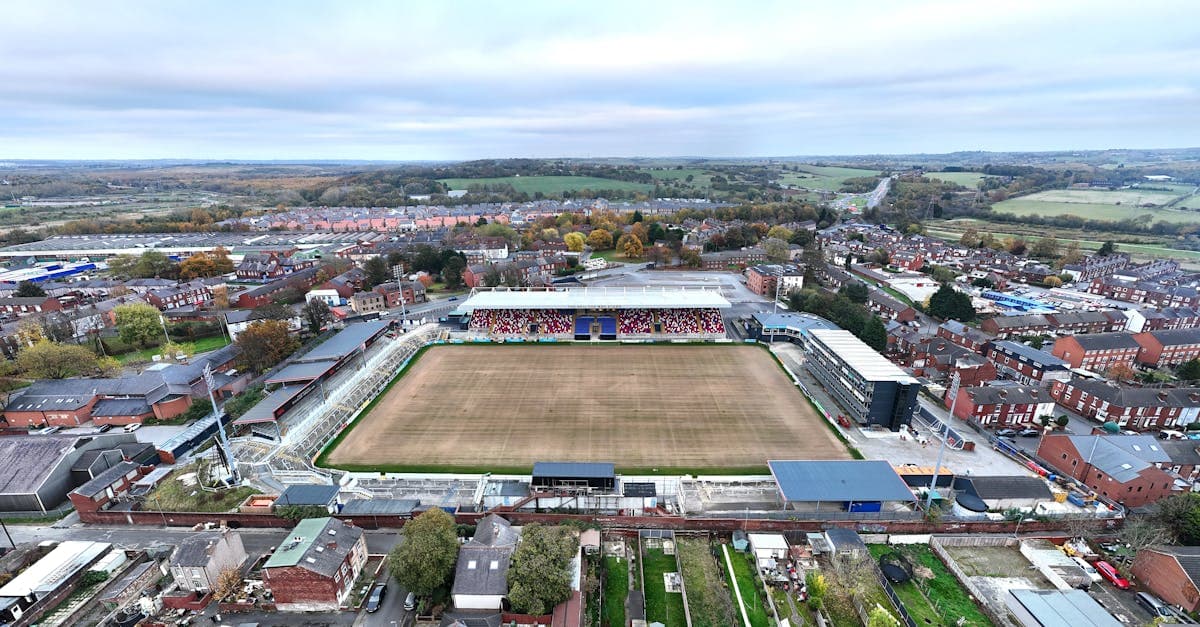 Aerial shot of a football stadium in a town, surrounded by houses and fields.