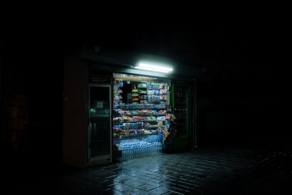 Shelves of groceries and a serving counter inside a small independent convenience store