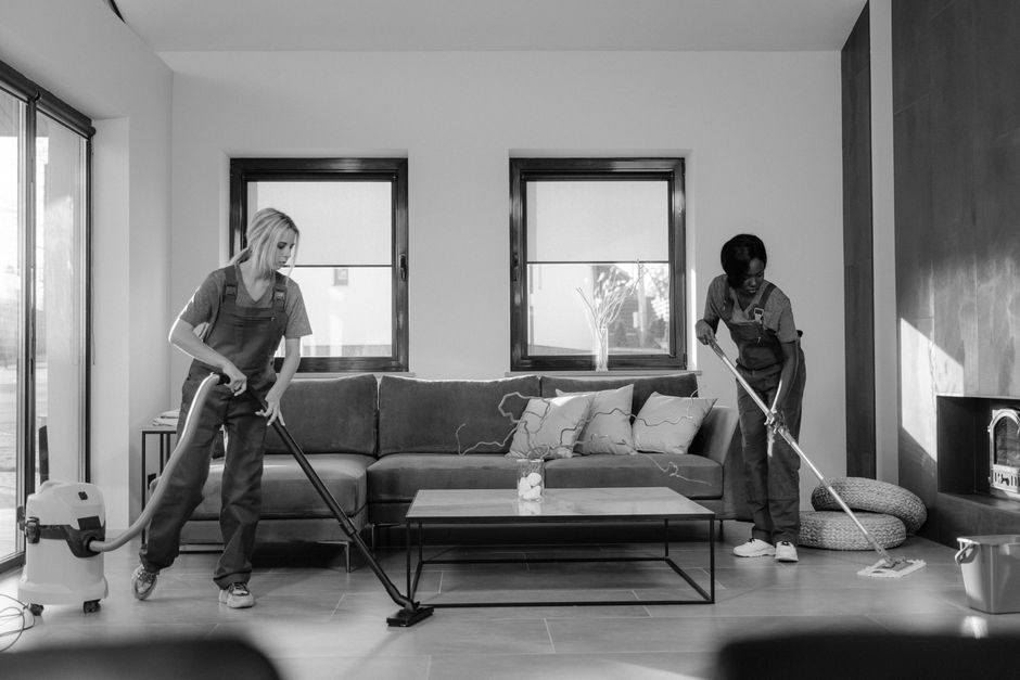 Commercial cleaning team servicing a corporate office at night while an operations manager reviews a facilities-management contract schedule